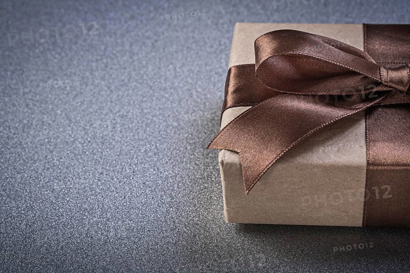 Boxed gift with brown knot on grey background copy space celebrations concept