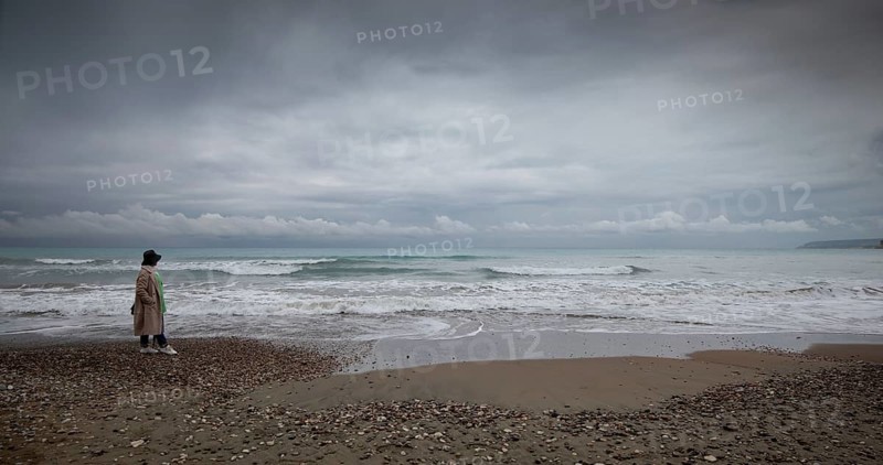 One woman walking on the coast beach. Stormy sky windy waves. Paphos Cyprus