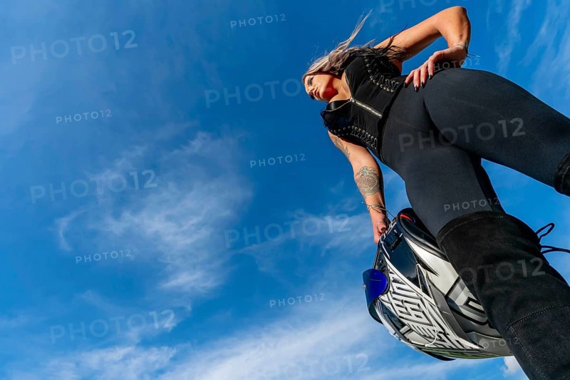 A stunning woman strikes a confident pose beside her high-performance motorcycle. With a fierce gaze and poised stance, she radiates power and passion, embodying the spirit of the open road, Troutman, United States of America