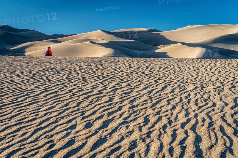 Lost in the sea of sand - a lonely hiker in a dunefield in Great Sand Dunes National Park, Colorado