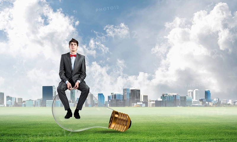 A businessman with glasses sits on a light bulb. concept of creativity in business