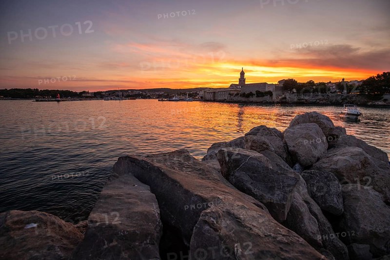 Town on a coast, with a stone fortification a harbour with a view of the sunset. Landscape photo of the town of Krk, Croatia, Europe