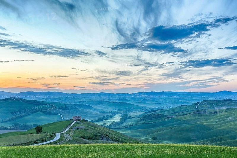 Italian valley in the dawn light with a farm on a hill