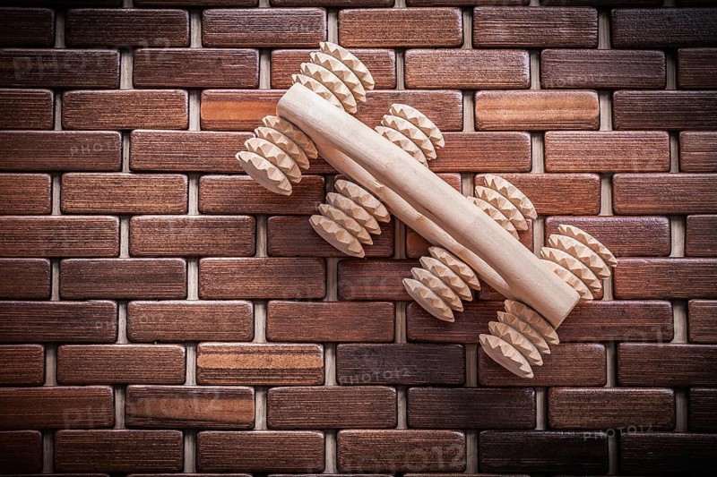 Wood massager with handle on textured wooden mat healthcare concept