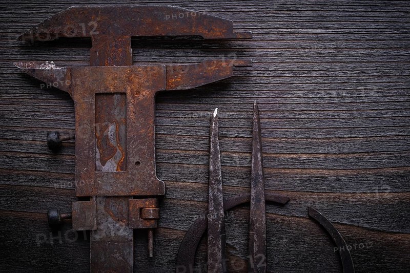 Top view of old-fashioned slide calipers on vintage wooden board