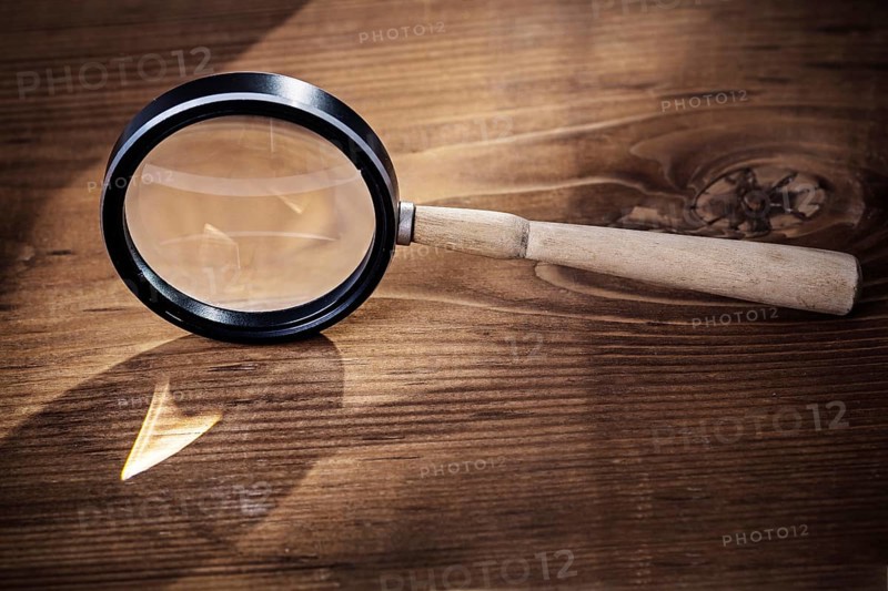 Vintage magnifer glass on old wooden board