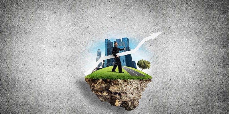 Conceptual image of young and confident business man in suit holding big white arrow in hands while standing on flying island against gray concrete background
