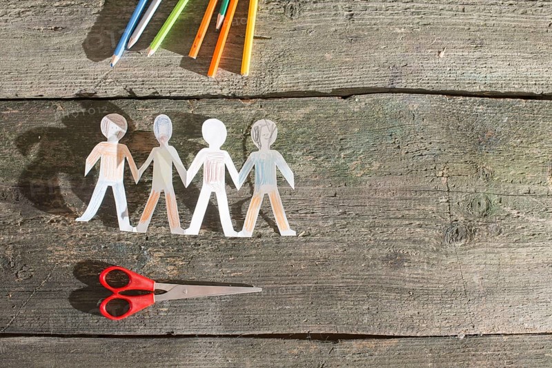 Paper made people figures. Painted white figures on wooden board