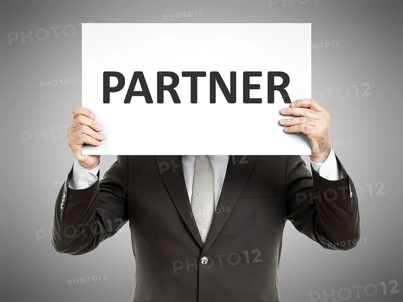 A business man holding a paper in front of his face with the text partner