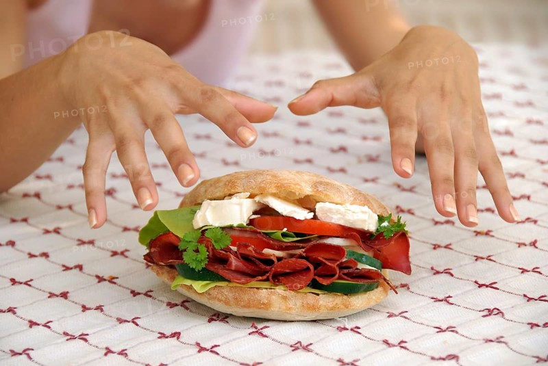Hungry girl hands over appetising big sandwich with ham and cheese