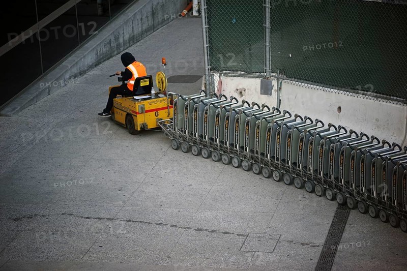 Los Angeles, United States - December 28, 2015: An airport employee at LAX airport pulls a vehicle and luggage cart up a ramp on 28 December 2015 in Los Angeles
