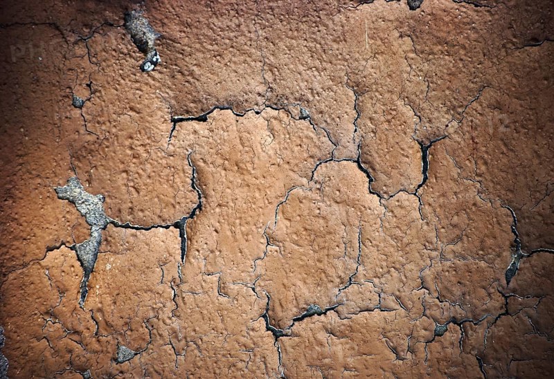 The close-up of peeling layers of plaster and paint on a concrete wall