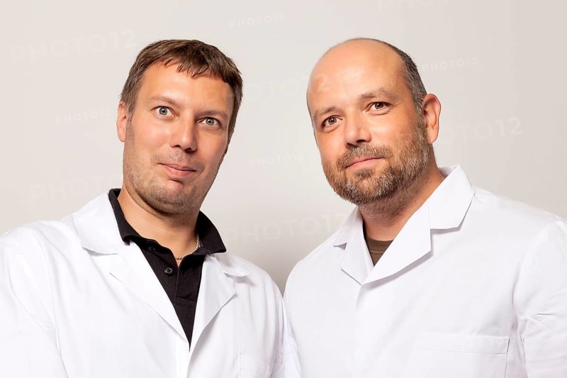 Two men in white coat smiling to the camera