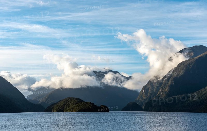 Sun rising over Doubtful Sound, Clouds hanging low on the mountains, South Island of New Zealand