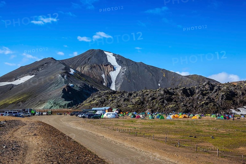 Rhyolite mountains surround the flat valley of National Park Landmannalaugar. Big tourist camp is located in the valley of the park