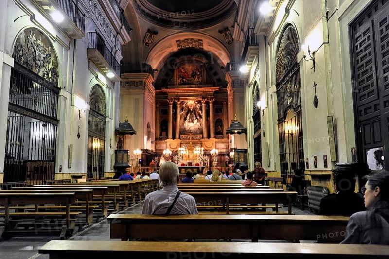 Madrid, Spain, Europe, Interior of a church with pews and an illuminated altar in the background, Europe