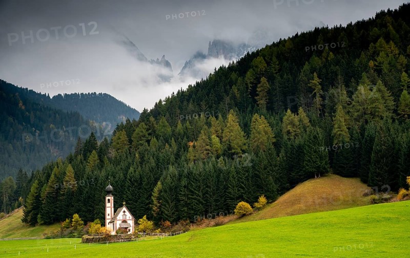 The small and beautiful church of Saint John, Ranui, Chiesetta di san giovanni in Ranui Runes South Tyrol Italy, surrounded by green meadow, forest and Dolomite mountains