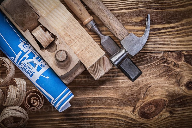 Blue construction plan shaving plane claw hammer chisel wooden studs shavings on wood board