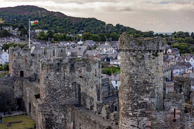 Conwy Castle, medieval castle with towers and surrounding town in a green landscape under a cloudy sky, Conwy, Wales, Great Britain