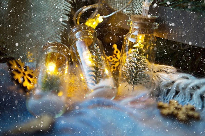 Fairy lights in a jar with a Christmas tree and snow close-up on a warm cozy plaid with wooden decor. Christmas and New Year, festive decor, comfort at home, preparation for celebration, fabulous mood