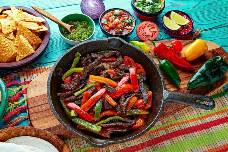 Beef fajitas in a pan with sauces chili and sides Mexican food