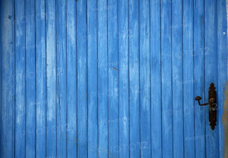 Blue old mediterranean wooden door detail with black handle