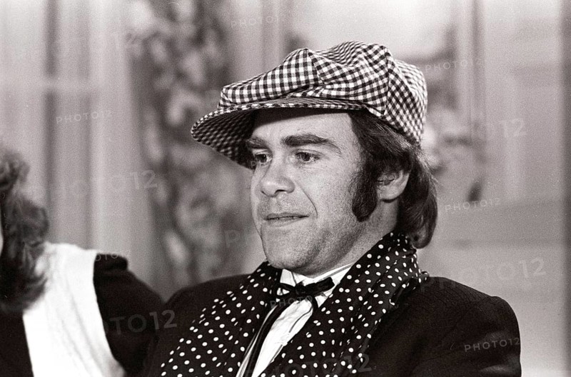 Elton John. English singer, songwriter born march 25 1947. Pictured wearing a chequered cap and a matching chequered scarf during a visit to Sweden 1978. Kristoffersson