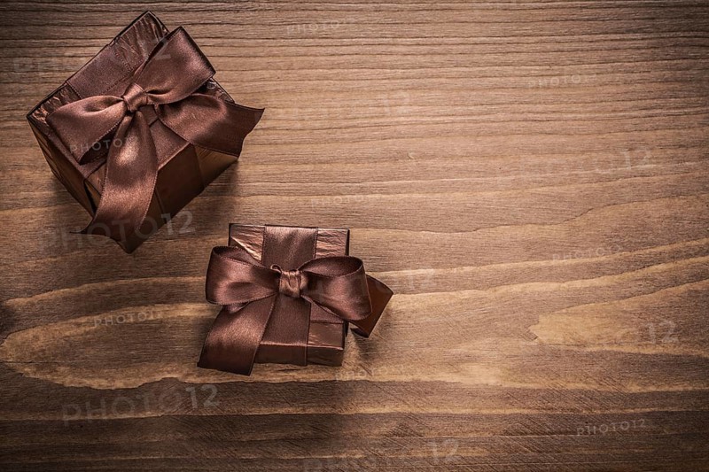 Packed glittery gift containers with bows on vintage wooden board