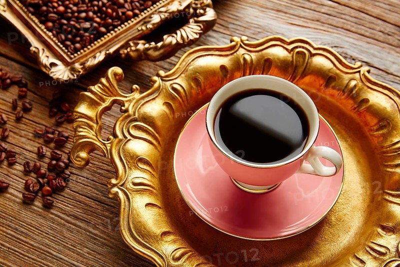 Coffee cup and beans on vintage golden tray in wooden old table