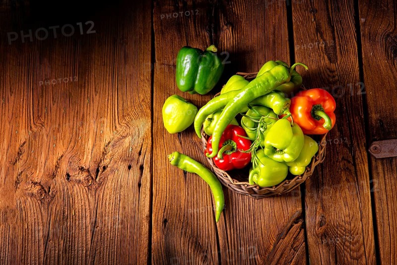 Various harvested peppers and hot peppers in a basket