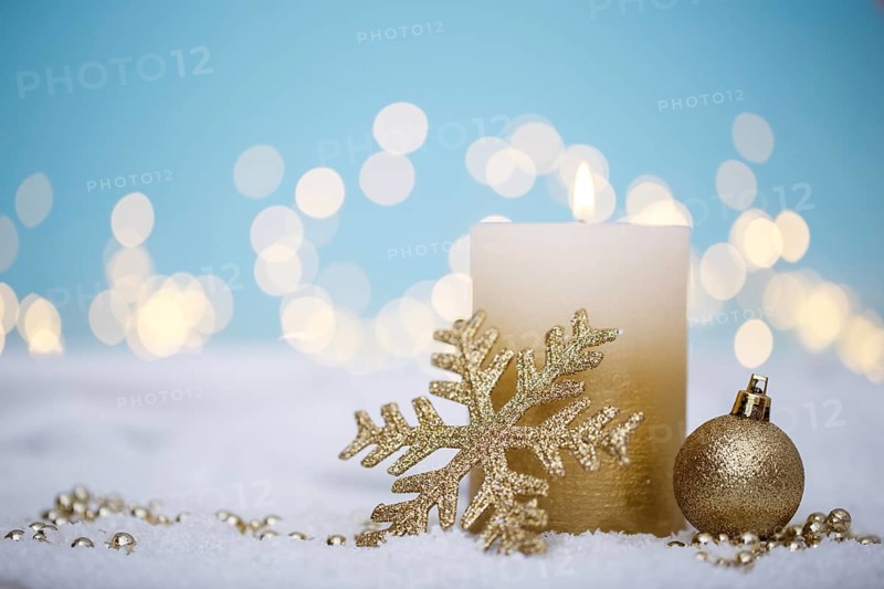 Christmas or new year candle with festive ornaments and bokeh lights on snow, family holidays