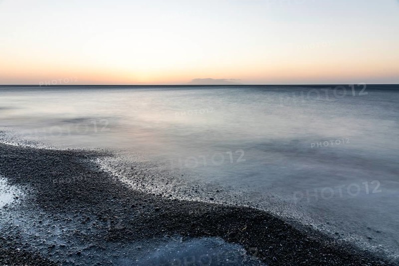 Morning atmosphere, sunrise over the sea, view from the lava beach to the island of Anafi, long exposure, Kamari, island of Santorini, Cyclades, Greece, Europe