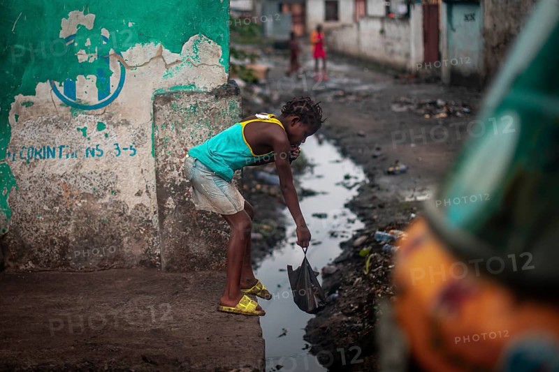 Child throwing rubbish into a gutter on the street, environmental pollution, poverty Kinshasa, Democratic Republic of the Congo, DR Congo