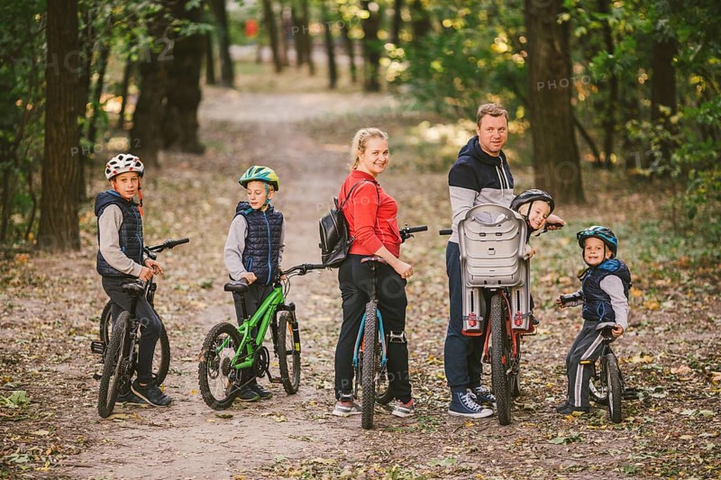 Parents and kids cycling on forest trail. family in warm clothes cycling autumn park. Family mountain bike on forest. active sports outdoor recreation. portrait Family Cycling Through Fall Woodland