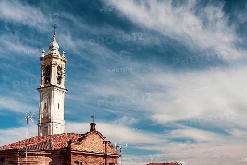 Historic church bell tower reaching out to a clear blue sky adorned with delicate clouds. Vigevano, Lombardy. Italy