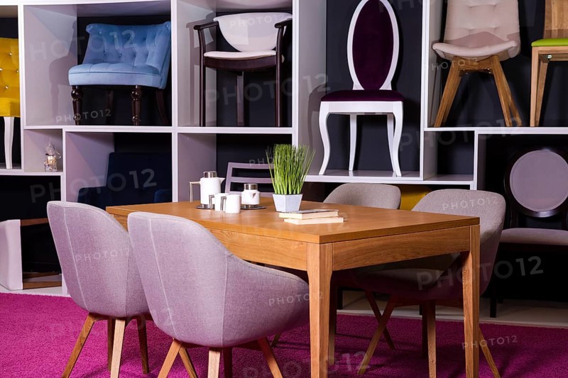 Shop, sale of furniture in a shopping centre. Exposure sample Dining wooden table with textile chairs in grey on a white shelf with furniture and a pink carpet