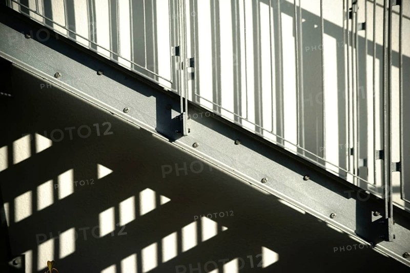 The façade of a residential building with an external staircase that casts a shadow