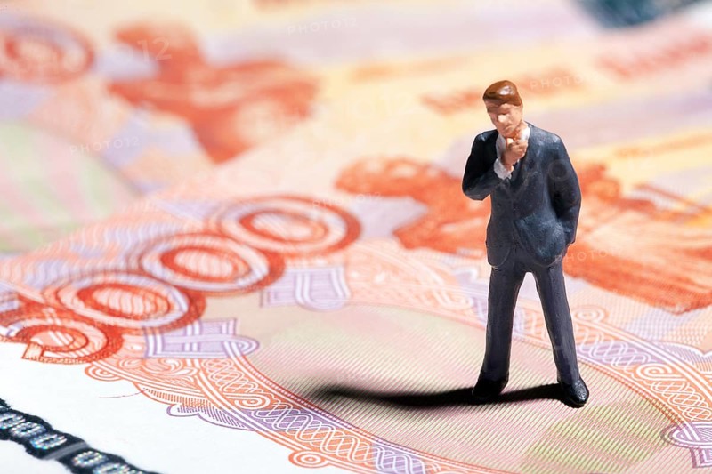 Miniature figurine businessman with 5000 rubles banknote on background. Concept
