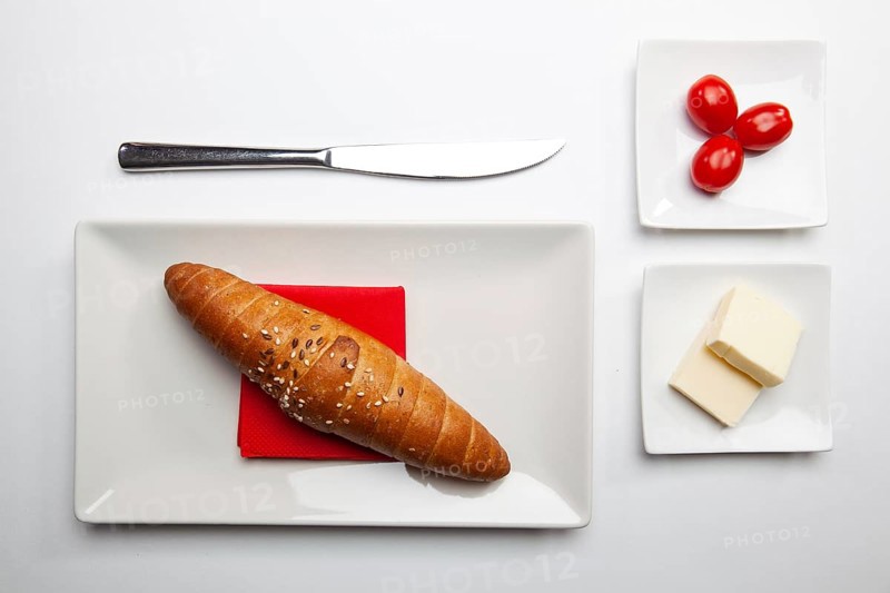 Healthy breakfast. Block of fresh butter, french baguette and red cherry tomatoes on the white table