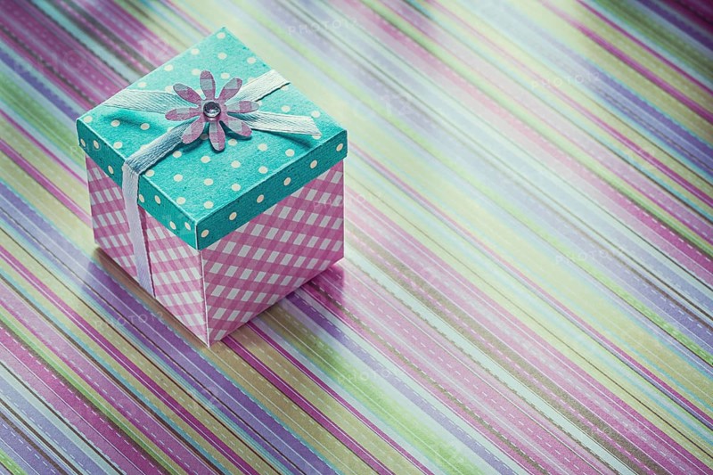 Wrapped gift box on stripy fabric background celebrations concept