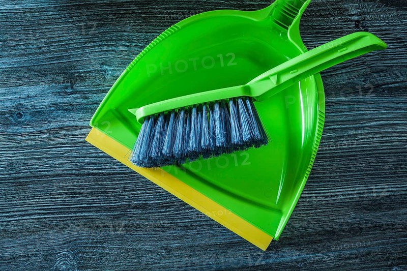 Plastic dustpan and brush set on wooden board