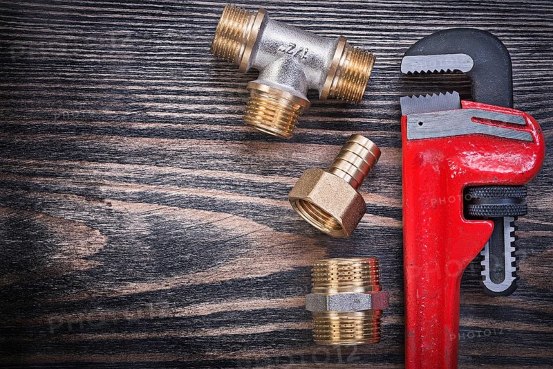 Set of monkey wrench brass equal tee nipple hose connector on wooden board plumbing concept