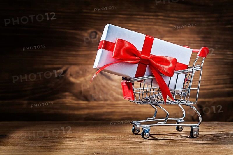 White giftbox in shopping cart on vintage wood