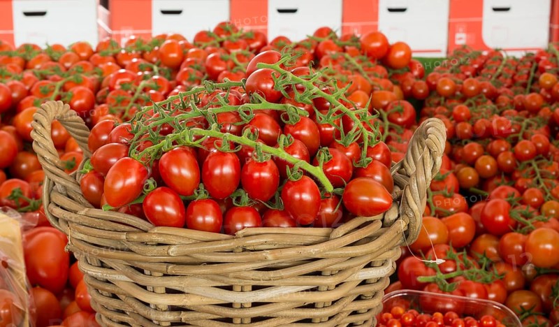 Reed basket with red tomatoes amid countless sizes of red tomatoes