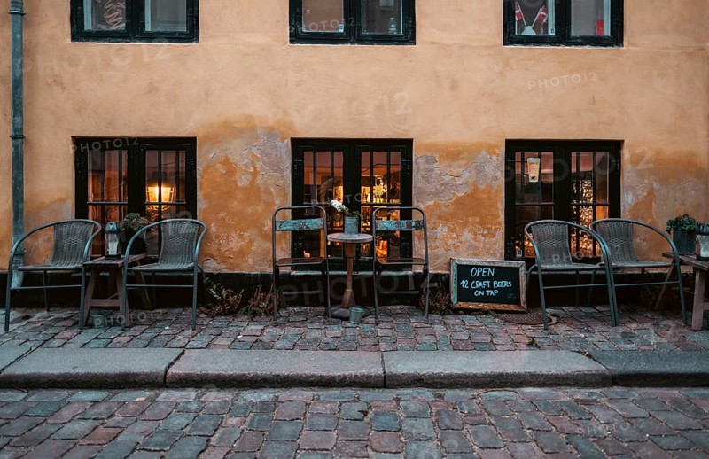 Outdoor cafe seating on cobblestone street with warm lighting and a rustic atmosphere in central Copenhagen, Denmark, Europe