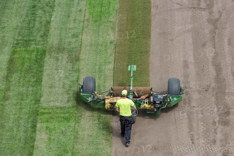Workers laying grass in a roll on a football field at the stadium in Lubin, Poland, Europe