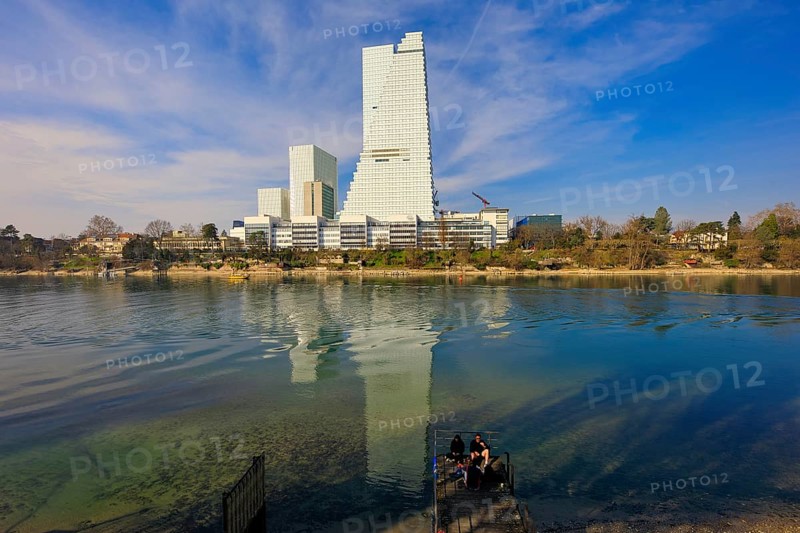 A person on a platform in front of large reflective office buildings, pharmaceutical company Roche, skyscrapers, towers, Rhine, Basel, Switzerland, Europe
