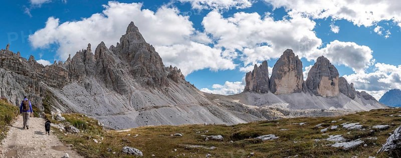 A female person hiking lonely with her dog around the Drei Zinnen mountains, the Dolomites in South Tirol