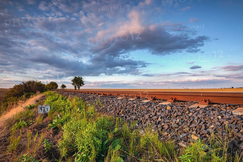 Old Railway tracks running through a field stretch to rural countryside at sunset. Single railway track at sunset, Czech Republic, Europe