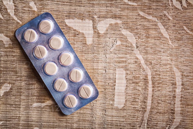 Pills in blister pack on vintage wooden board with organized copyspace medical concept